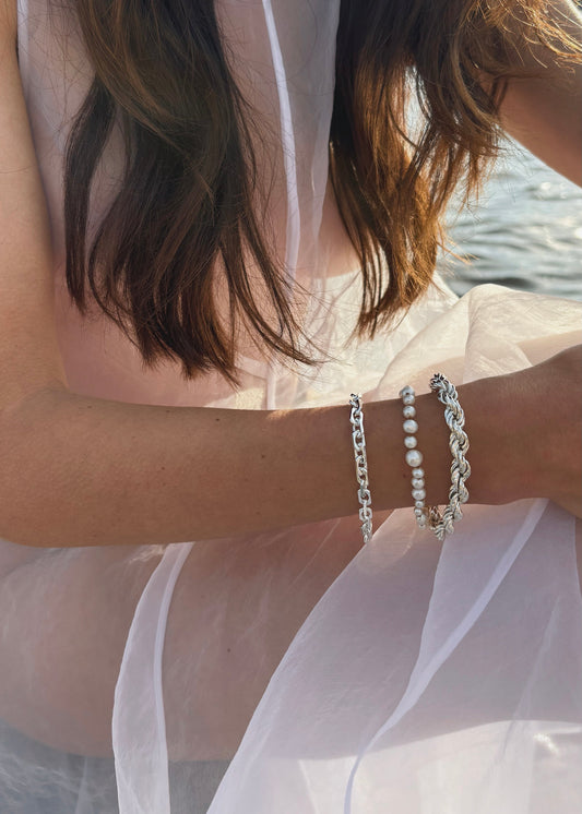 Close up look on silver and pearl bracelets. Minimalist design and effortless elegance to elevate your style this summer. Timeless jewelry to wear everyday.