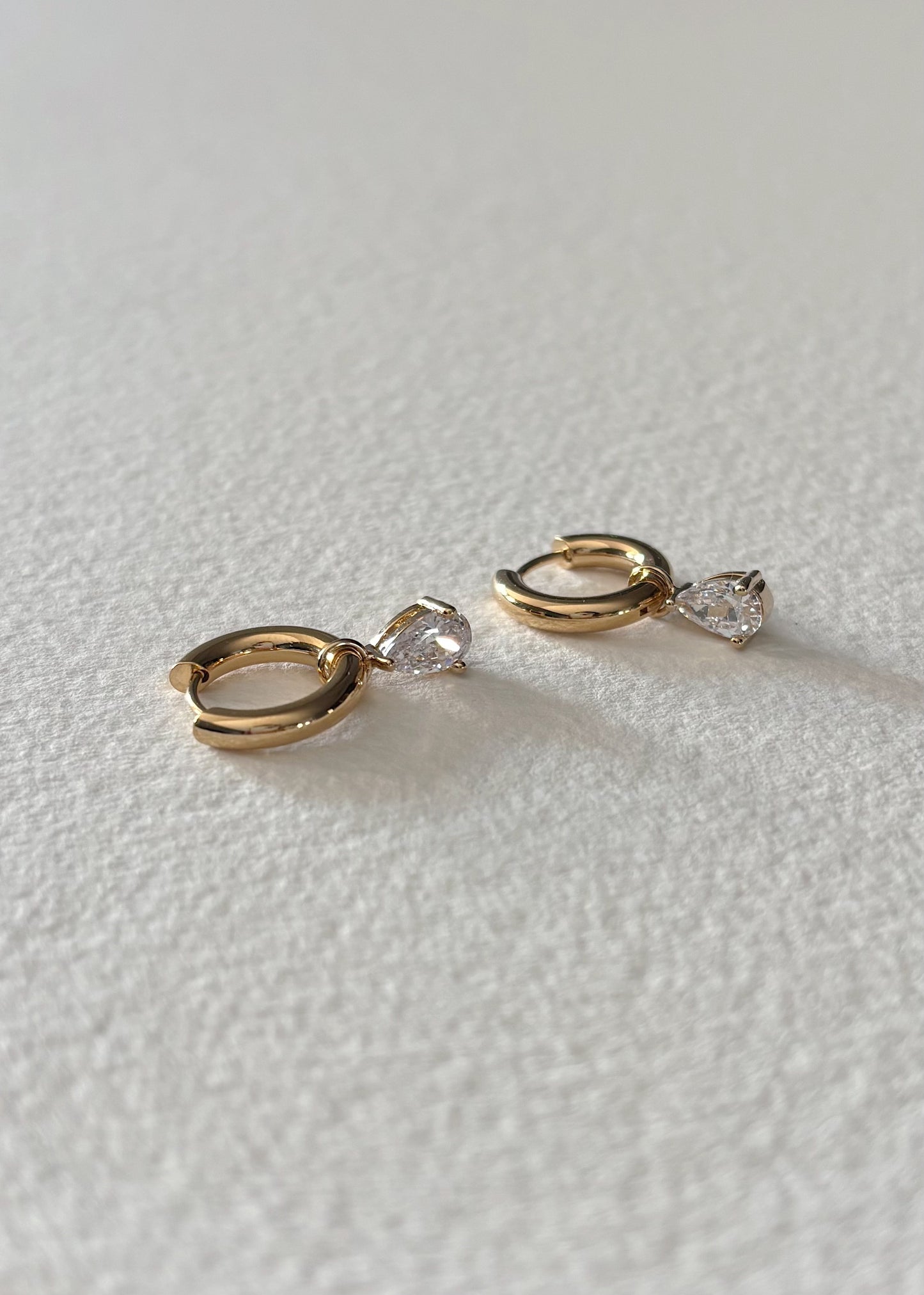 Gold hoop earrings adorned with semi-precious stones, featuring a timeless silhouette that embodies modern elegance, refined detail, and soft radiant brilliance.